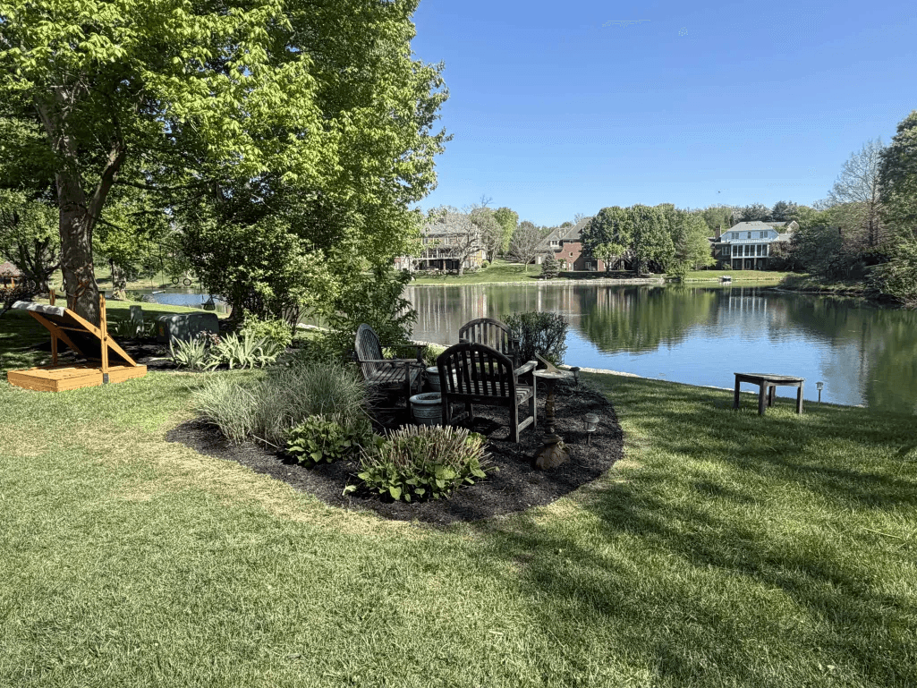 Lakefront sitting area with ornamental planting bed and lush lawn